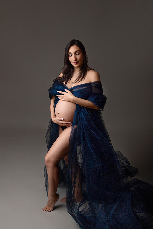 Mujer embarazada con vestido azul, sesión premamá en estudio
